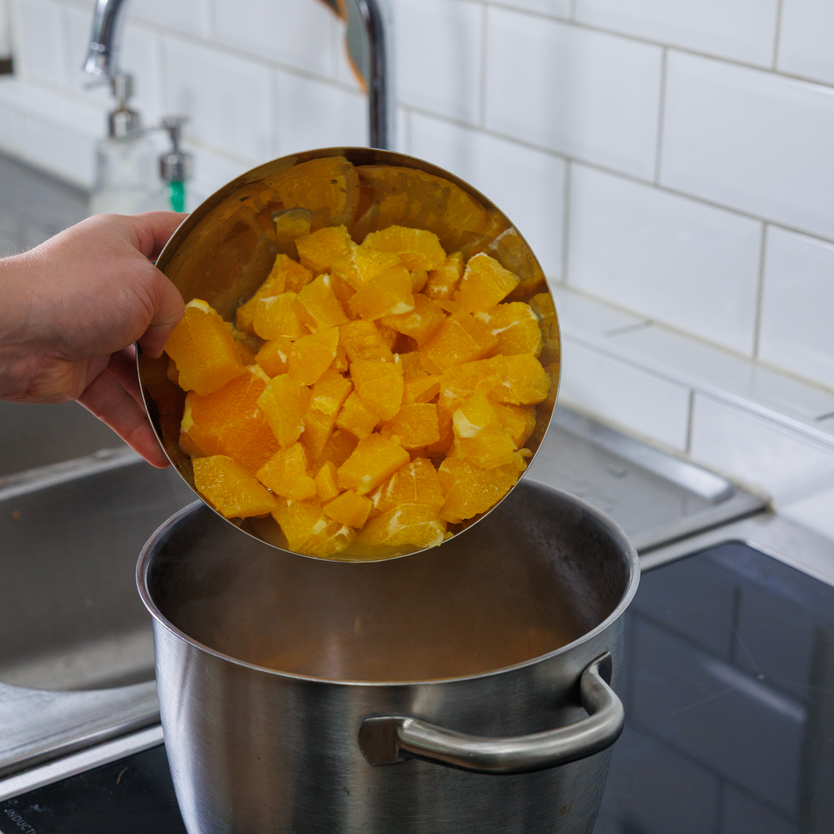 Förstorad bild: Häller ner skuret apelsinkött i kastrullen