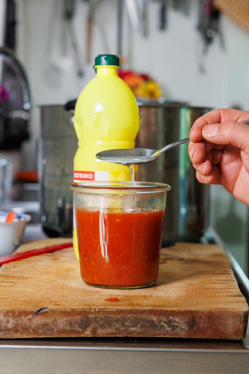 Buteljerad citronjuice tillsätts i en burk med tomatsås