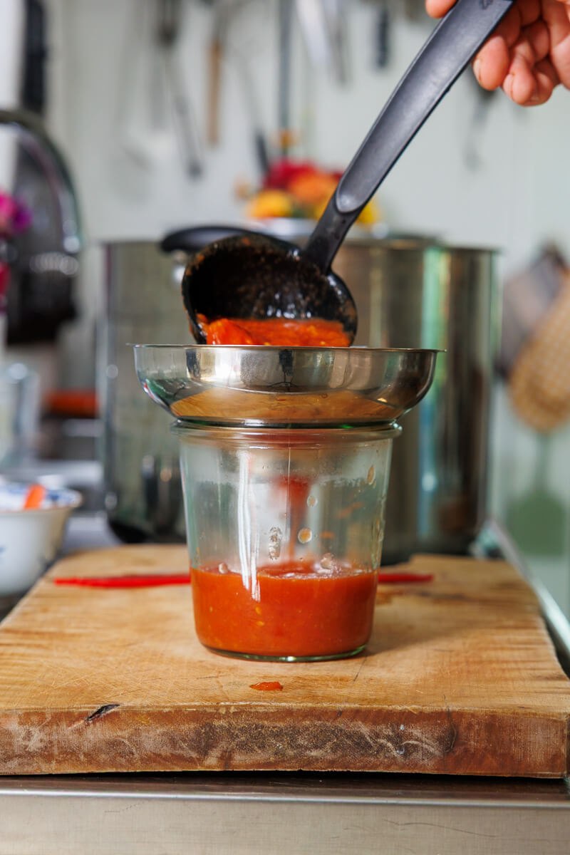 Varm tomatsås hälls i en ren glasburk