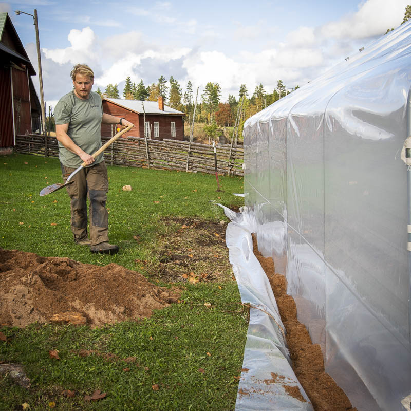 Nedgrävning av plasten på långsidan. Sand fungerar, men jord går också bra. Det viktiga är att plasten hålls nere av tungt material.