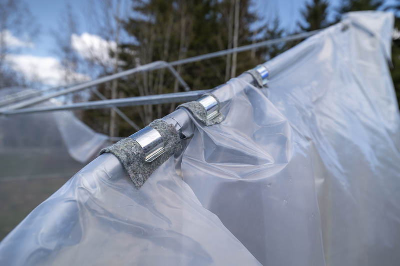 Bågklämmor vid gavelplastmontering. En bit tyg mellan klämma och plast minskar nötning och gör klämman lättare att hantera.