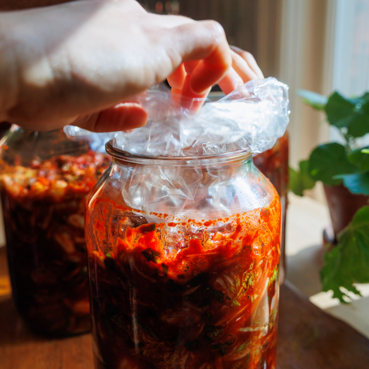Kimchi i glasburk med en påse ovanpå som tyngd.